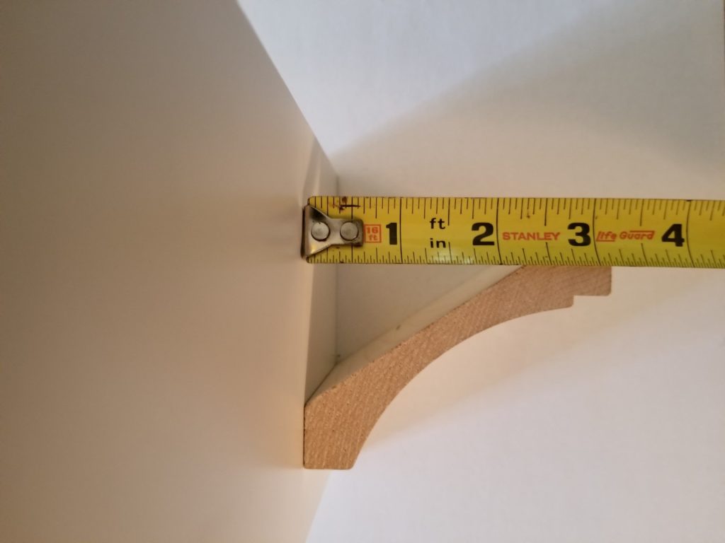 Set the top of the crown moulding against a flat surface and measure down to the bottom to get the overall height.