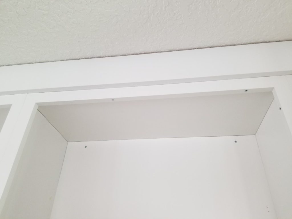 Attach riser moulding through the top of the face frame with screws, leaving a 3/4" reveal overhanging the cabinet face.